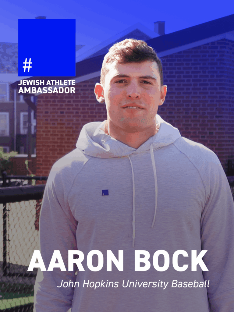 Aaron Bock, John Hopkins University baseball player, wearing a gray hoodie with a blue square pin, identified as a Jewish Athlete Ambassador.