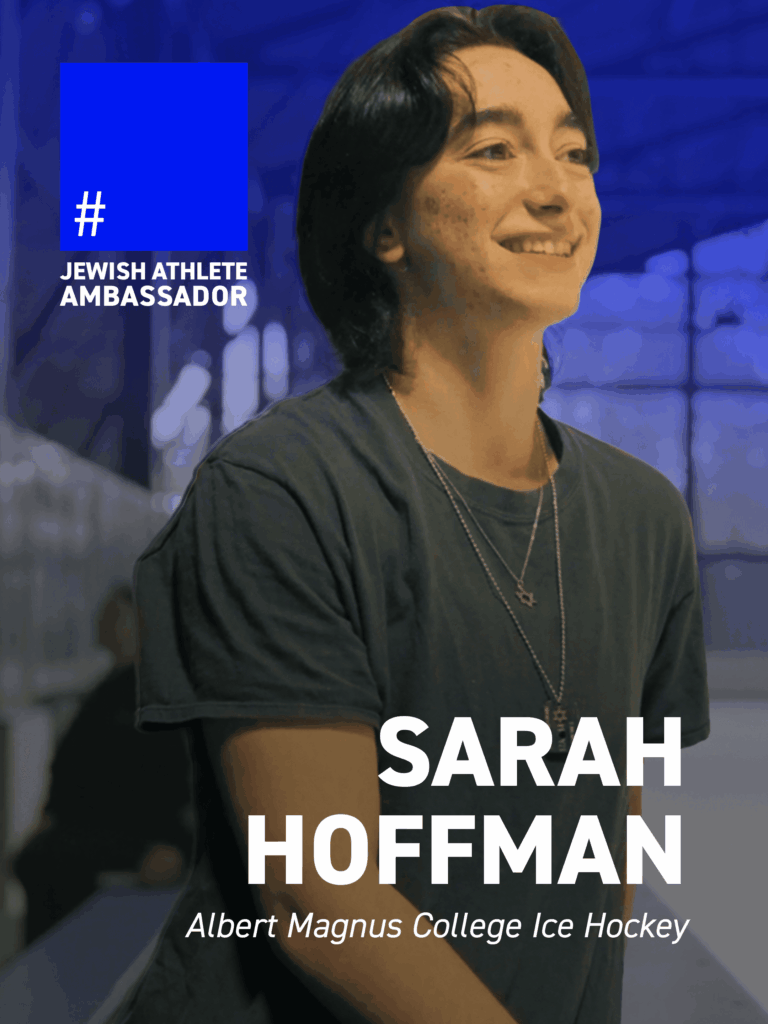 Sarah Hoffman, Albert Magnus College ice hockey player, smiling at an indoor rink, featured as a Jewish Athlete Ambassador.