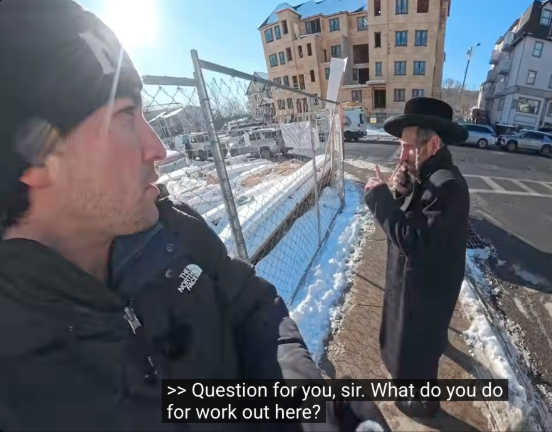 Frame from the YouTube video, depicting Oliveira asking a Hasidic man on the sidewalk, "Question for you sir. What do you do for work out here?"