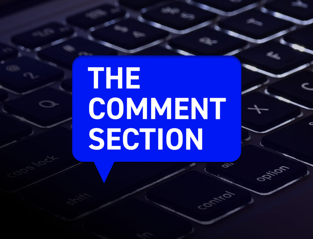 A close-up of a black computer keyboard with a large bright blue speech bubble centered over it. Inside the bubble, bold white uppercase text reads: “THE COMMENT SECTION.” The image suggests online discussions or social media conversations.