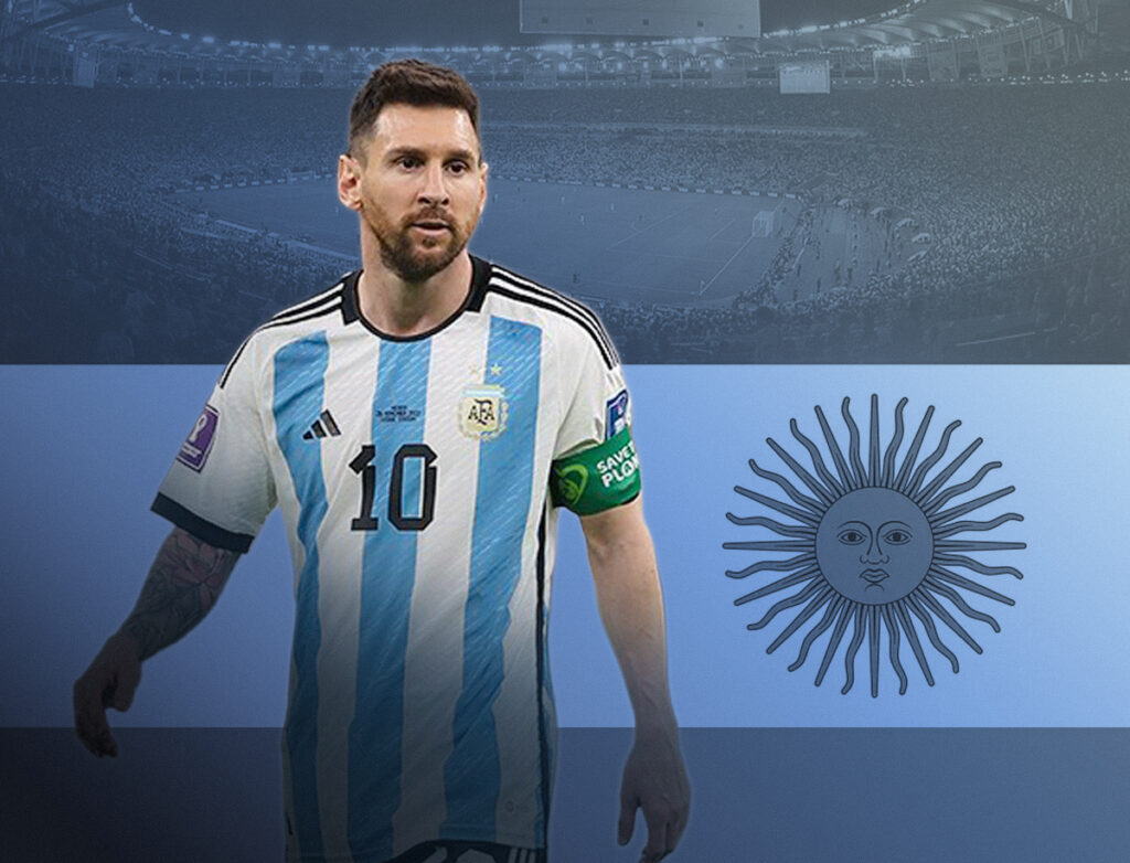 Lionel Messi stands in front of a large Argentine flag. A packed stadium fills the background, faded in blue-gray tones, creating a dramatic sports-themed composition. The player wears a green captain's armband on his left arm and looks ahead with a focused expression.