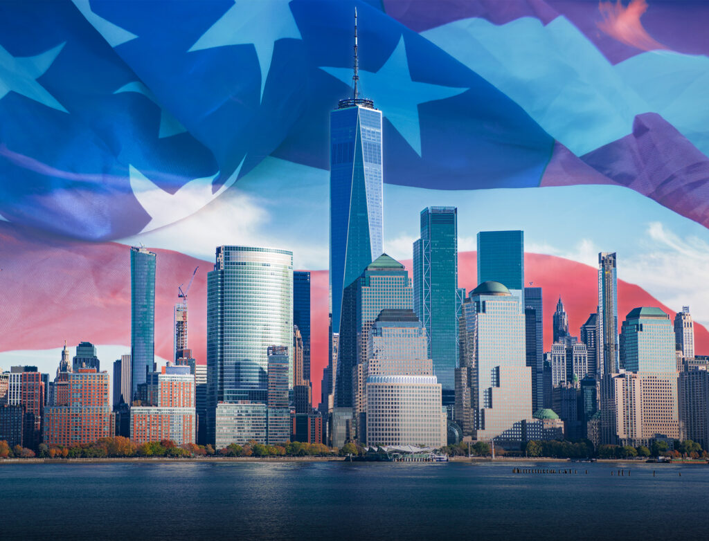 Lower Manhattan skyline featuring One World Trade Center, overlaid with a semi-transparent American flag.